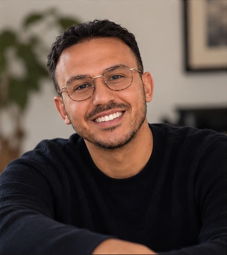 Saad Benryane smiling, wearing glasses and a black sweater.